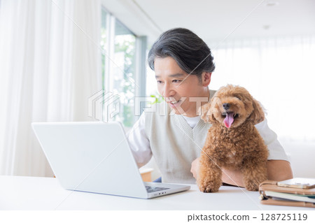 遠距辦公：一名男子一邊抱著狗狗一邊工作 128725119