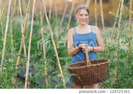 Young woman with basket in cottage garden 128725161