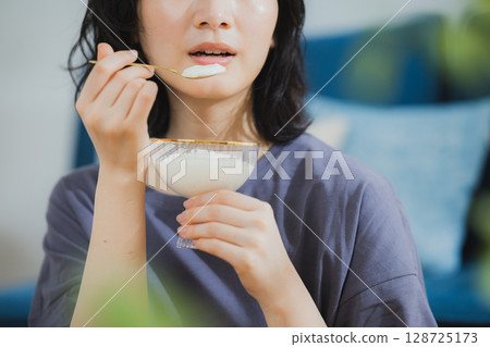 Young woman eating yogurt 128725173