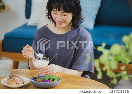 Young woman eating yogurt 128725176