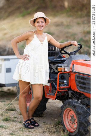 Girl in summer sundress near tractor 128725183