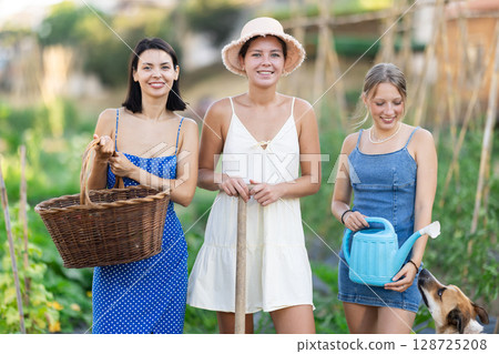 Three women and dog in garden in country house 128725208