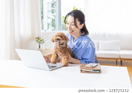 Telework: A middle-aged woman working while holding a dog 128725212