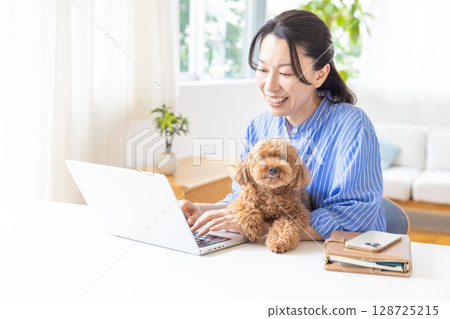 遠距辦公：一位中年婦女抱著狗狗工作 128725215