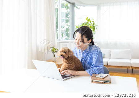 Telework: A middle-aged woman working while holding a dog 128725216