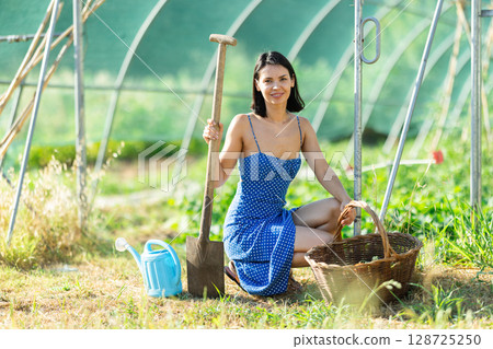 Adult woman works in garden greenhouse Adult woman works in garden greenhouse 128725250