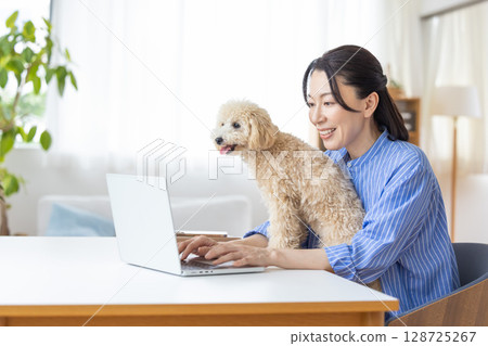遠距辦公：一位中年婦女抱著狗狗工作 128725267