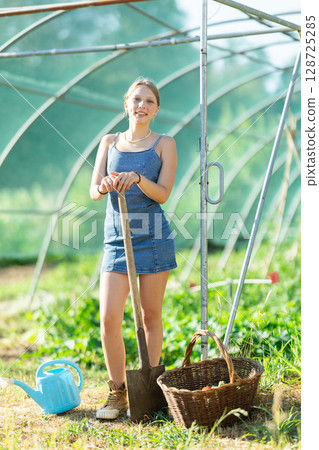 Young woman works in garden greenhouse Young woman works in garden greenhouse 128725285