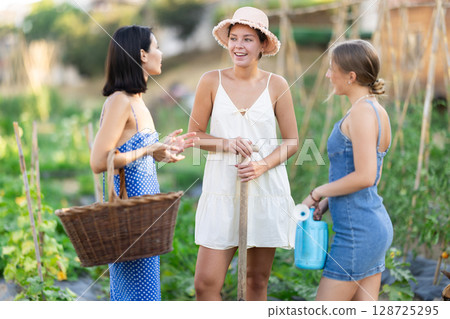 Three women talking in garden of country house Three women talking in garden of country house 128725295