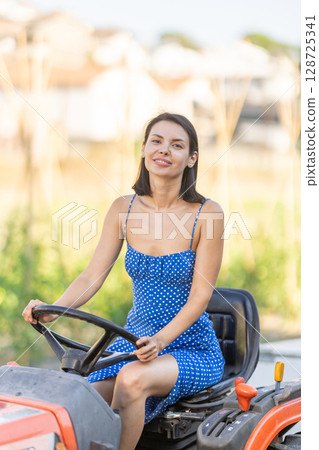 Adult woman driving tractor in countryside Adult woman driving tractor in countryside 128725341