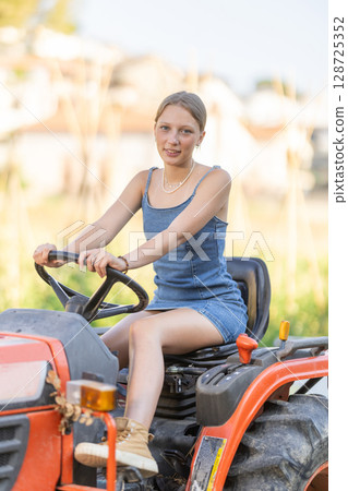Young woman driving tractor in countryside Young woman driving tractor in countryside 128725352