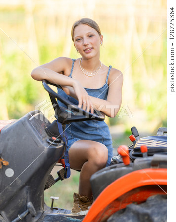 Girl in summer sundress near tractor 128725364