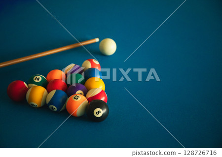 Billiard game setup with colorful balls and cue stick on blue felt Billiard game setup with colorful balls and cue stick on blue felt 128726716