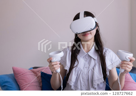 A Japanese woman enjoying virtual reality with VR goggles in the living room at home A Japanese woman enjoying virtual reality with VR goggles in the living room at home 128727662