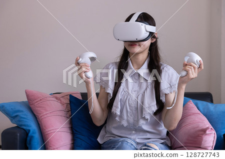 A Japanese woman enjoying virtual reality with VR goggles in the living room at home A Japanese woman enjoying virtual reality with VR goggles in the living room at home 128727743