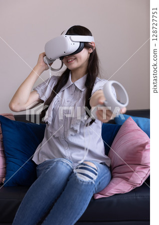 一位日本女性在家中客廳戴著 VR 眼鏡享受虛擬現實 128727751