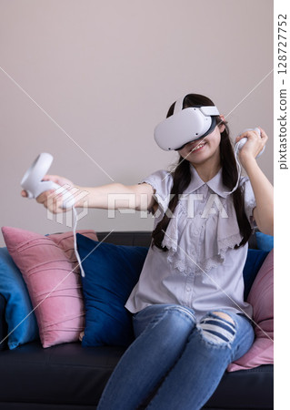 一位日本女性在家中客廳戴著 VR 眼鏡享受虛擬現實 一位日本女性在家中客廳戴著 VR 眼鏡享受虛擬現實 128727752