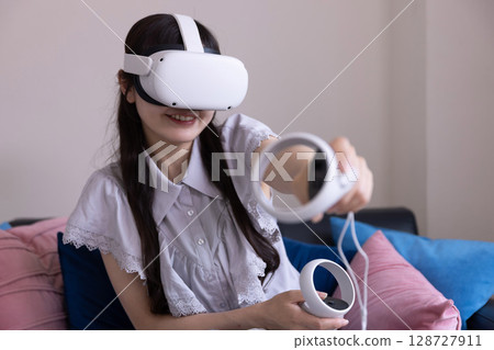 A Japanese woman enjoying virtual reality with VR goggles in the living room at home 128727911