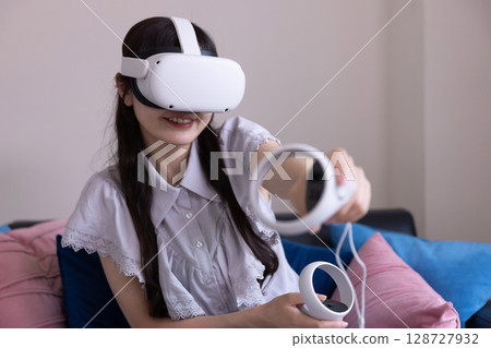 A Japanese woman enjoying virtual reality with VR goggles in the living room at home 128727932