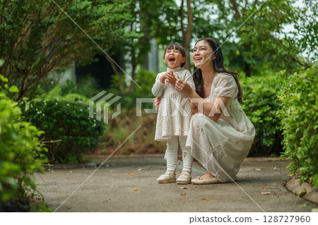 happy mother and toddler girl with Ruellia simplex or Mexican petunia flower in garden 128727960