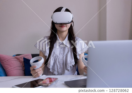 A Japanese woman enjoying virtual reality with VR goggles in the living room at home A Japanese woman enjoying virtual reality with VR goggles in the living room at home 128728062