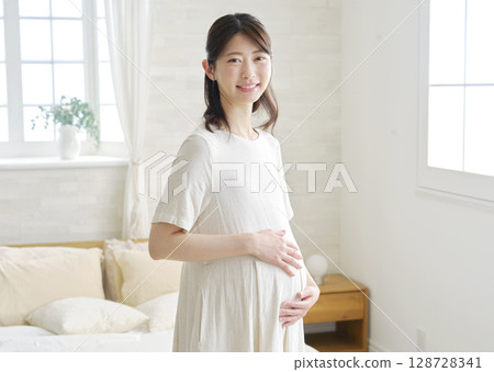 Pregnant woman portrait at home looking at camera 128728341