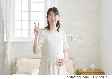 Pregnant woman peace sign at home 128728342