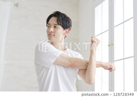 Man stretching his arms at home Man stretching his arms at home 128728349