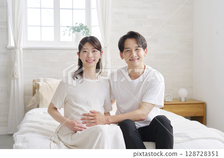 Portrait of a couple: husband touching his pregnant wife's belly Portrait of a couple: husband touching his pregnant wife's belly 128728351