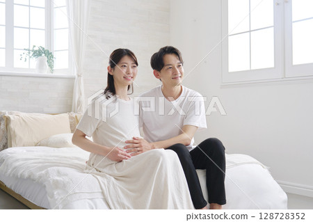 Portrait of a couple: husband touching his pregnant wife's belly Portrait of a couple: husband touching his pregnant wife's belly 128728352