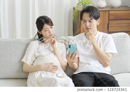 Pregnant wife and husband holding smartphones Pregnant wife and husband holding smartphones 128728361
