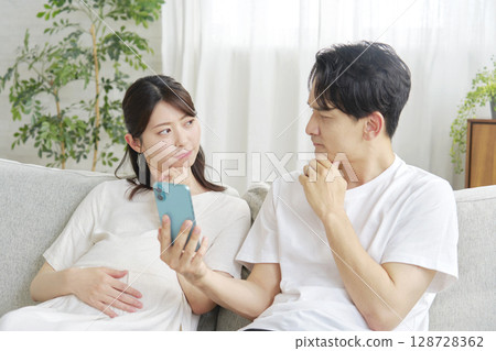 Pregnant wife and husband holding smartphones 128728362