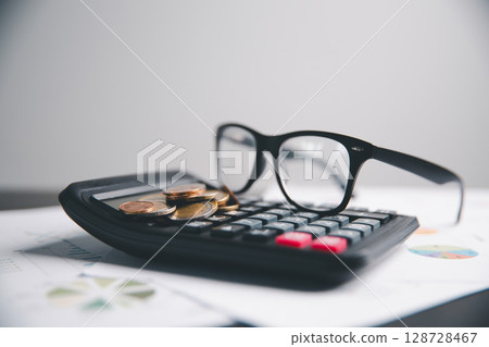 Financial calculate accountant blur background close up on calculator with graph chart banner bank office desk. Finance Concept tax banking money expense accounting budget businessman use calculator. Financial calculate accountant blur background close up on calculator with graph chart banner bank office desk. Finance Concept tax banking money expense accounting budget businessman use calculator. 128728467