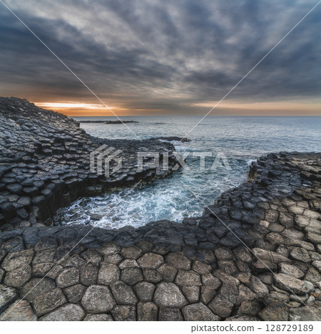 Ganh Da Dia in Phu Yen province in Vietnam at sunset. Landscape with black volcanic basalt columns Da Dia reef on rocky beach by the sea 128729189