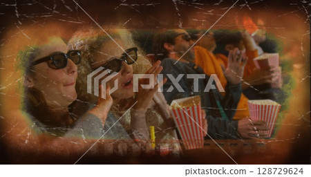 Leaning forward moviegoer friends waving hands in dark theater, with 3D glasses and popcorn buckets 128729624