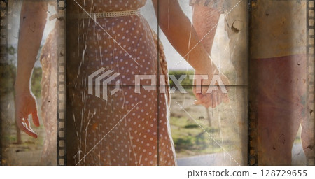 Walking couple wearing brown polka dot dress and red shorts on sunlit rural path, filmstrip overlay Walking couple wearing brown polka dot dress and red shorts on sunlit rural path, filmstrip overlay 128729655