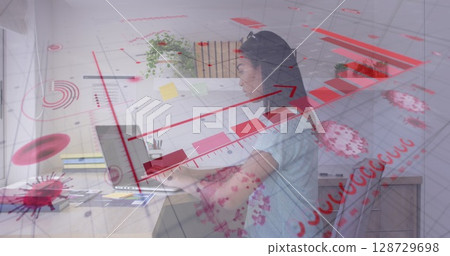 Woman typing on laptop in home office, with notebooks sticky notes pen holder plant and glasses 128729698