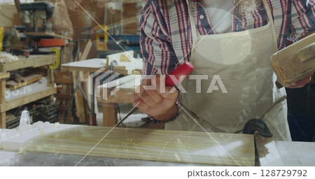 Smoothing mature carpenter shaping slatted wooden panel at workshop, with red-handled tool 128729792