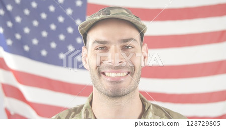Smiling soldier in camouflage uniform and cap standing before American flag, with patriotic theme Smiling soldier in camouflage uniform and cap standing before American flag, with patriotic theme 128729805