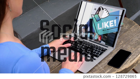Adult Korean man typing on laptop on outdoor terrace, with LIKE overlay and smartphone, copy space 128729865