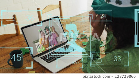 Smiling woman adjusting headband at wooden dining table, with laptop, shamrock confetti, copy space 128729866