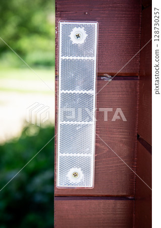 Close-Up of Mounted Reflector Panel on Wooden Wall in Sunlight. 128730257