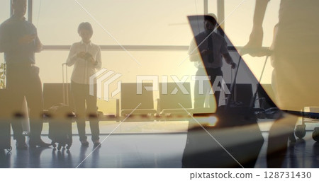 Standing business travelers checking smartphones at airport gate lounge, holding rolling suitcases Standing business travelers checking smartphones at airport gate lounge, holding rolling suitcases 128731430