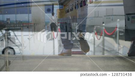 Moving traveler wearing white blouse pencil skirt pulling suitcase at airport check-in, with kiosks Moving traveler wearing white blouse pencil skirt pulling suitcase at airport check-in, with kiosks 128731438