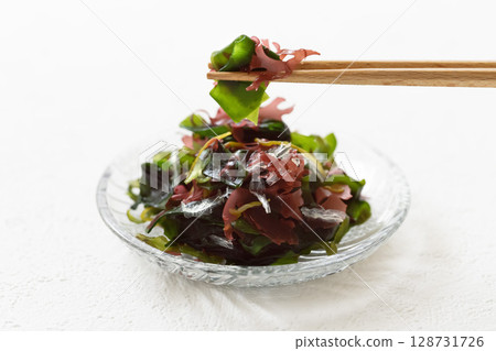 白色背景下用筷子夾海藻沙拉 白色背景下用筷子夾海藻沙拉 128731726