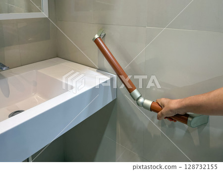 Senior woman holding on handrail for safety in bathroom 128732155