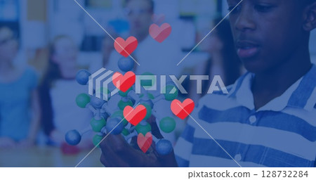 Examining teen boy in striped shirt holding molecular model inside science classroom, copy space 128732284