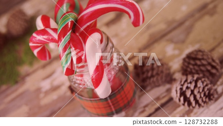 Showcasing glass jar with plaid ribbon holding candy canes on rustic tabletop with pinecones 128732288