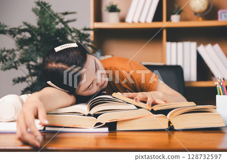 Asian girl doing homework and studying at home. woman using laptop at desk write notes watching webinar, study online, look at learn web class or having virtual call meeting remote working from home. 128732597
