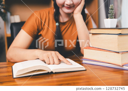 Asian girl doing homework and studying at home. woman using laptop at desk write notes watching webinar, study online, look at learn web class or having virtual call meeting remote working from home. 128732745